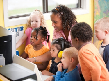 A kindergarten teacher with children at the computer