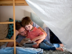 Father and son using an electronic tablet on bunk beds
