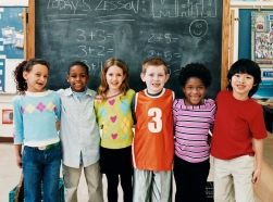 Six children standing in front of a chalkboard during a math lesson