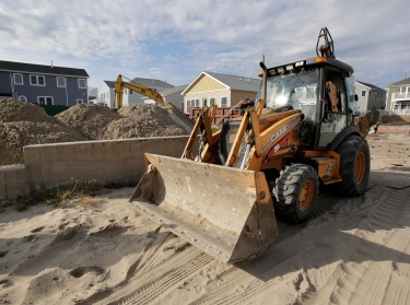 A bulldozer is parked in the Queens borough of New York where a concrete foundation is all that remains of a house that burned to the ground during Superstorm Sandy in October 2012