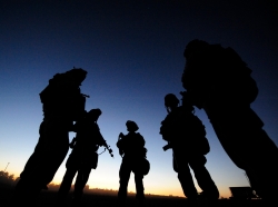 A silhouette of service members standing in a circle