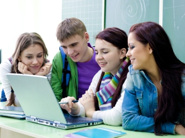 Group of young students studying in the classroom with a laptop