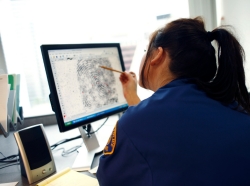 A police officer examining a fingerprint on a monitor