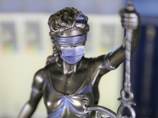 A statue of Lady Justice wearing a face mask