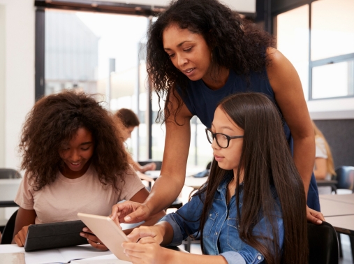 A high school teacher helping students use tablets