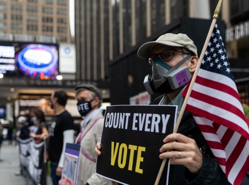 A man holds a sign outside Madison Square Garden, which is used as a polling station, on the first day of early voting in Manhattan, New York, October 24, 2020