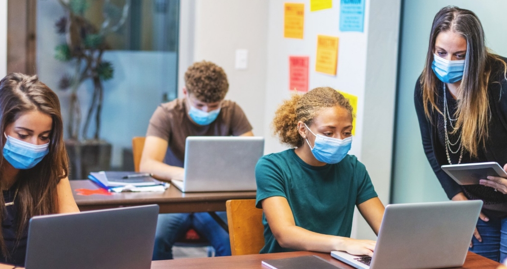 A teacher and students working on computers during class