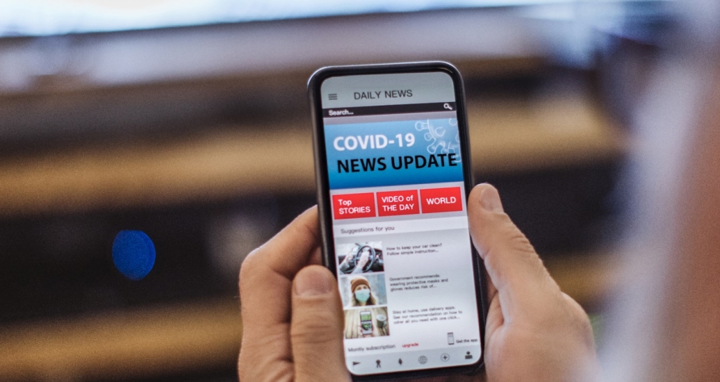 A person looks at a COVID-19 news update on their cell