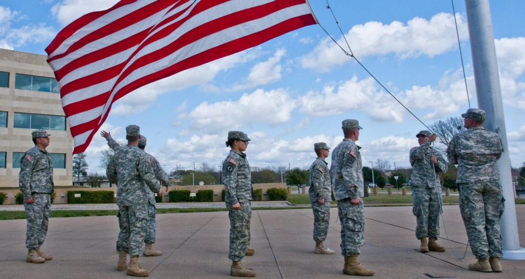 A formation of U.S. Army soldiers with III Corps and Fort Hood honor the American flag as they lower it during the Retreat ceremony, March 27, 2014