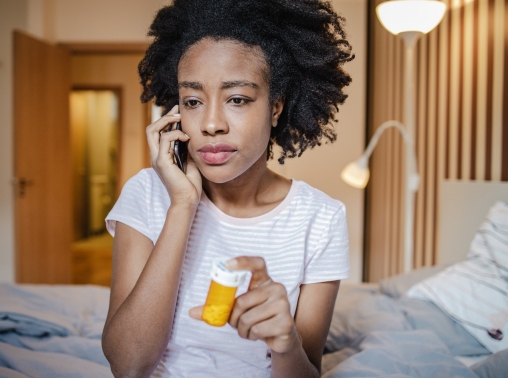 Woman at home on the phone holding a prescription bottle