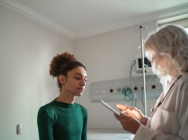 Doctor talking to patient at hospital room with a digital tablet, photo by FG Trade/Getty Images