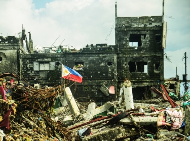 Photograph image of Philippine flag standing on a war torn city of Marawi in the Philippines.