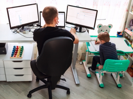 A father works from home while his child plays next to him