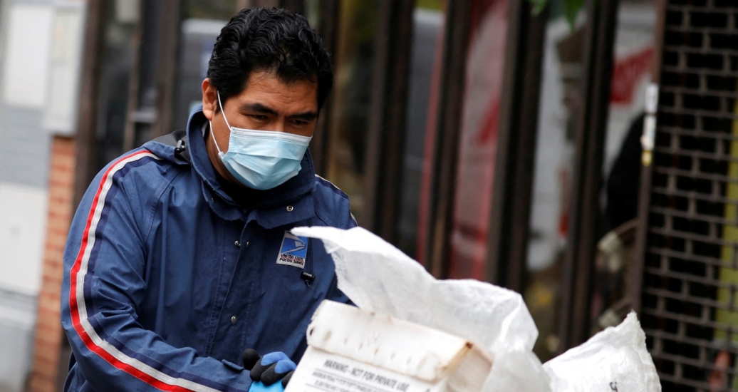 A USPS mail carrier delivers mail in the rain on Manhattan's Upper West Side, April 13, 2020