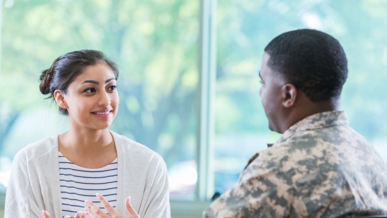 Military officer talks with young woman in recruitment office, photo by SDI Productions/Getty Images