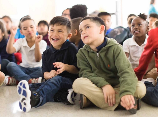 Children sit on the floor listening in a group