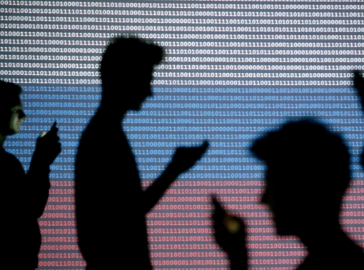People are silhouetted as they hold mobile devices in front of a screen projected with a binary code and a Russian flag, in Zenica, Bosnia and Herzegovina, October 29, 2014, photo by Dado Ruvic/Reuters
