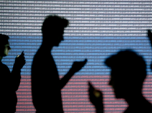 People silhouetted as they hold mobile devices in front of a screen projected with a binary code and a Russian flag, Zenica, Bosnia and Herzegovina, October 29, 2014