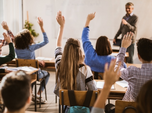 High school students raise their hands during class