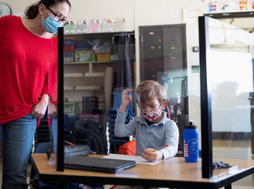 A teacher checks a student's work as students return to school when COVID-19 restrictions are lifted in Philadelphia, Pennsylvania, March 8, 2021