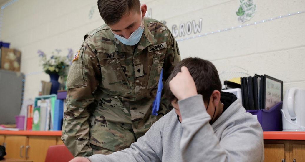 National Guard Specialist Austin Alt assists a student as he fills in as a substitute teacher due to staffing shortages caused by COVID-19 at Pojoaque Valley Middle School in Pojoaque, New Mexico, January 28, 2022