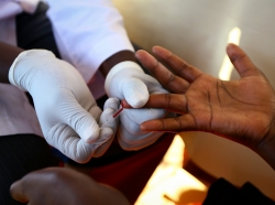 A doctor draws blood from a man to check for HIV/AIDS at a mobile testing unit in Ndeeba, Uganda, May 16, 2014