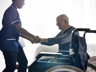 Nurse helping an elderly man out of a wheelchair