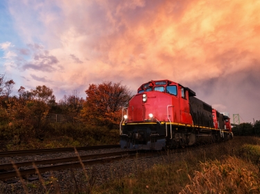 A freight train in a rural area with a sunset background