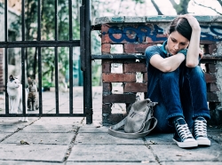 Adolescent girl sitting on sidewalk
