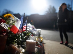 A passerby pauses near a makeshift memorial with U.S. and French flags outside the French embassy in Washington, November 16, 2015