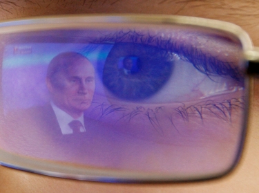 Russian President Vladimir Putin is reflected in the glasses of a cadet watching Putin on TV at a military school outside Rostov-on-Don, Russia, December 20, 2012