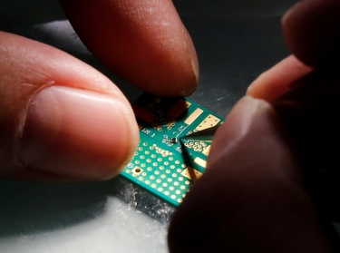 A researcher plants a semiconductor on an interface board during a research work to design and develop a semiconductor product at Tsinghua Unigroup research centre in Beijing, China, February 29, 2016, photo by Kim Kyung-Hoon/Reuters