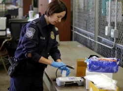 A U.S. Customs and Border Protection officer opens a plastic bottle to test the pills inside at the International Mail Facility at O'Hare International Airport in Chicago, Illinois, November 29, 2017, photo by Joshua Lott/Reuters