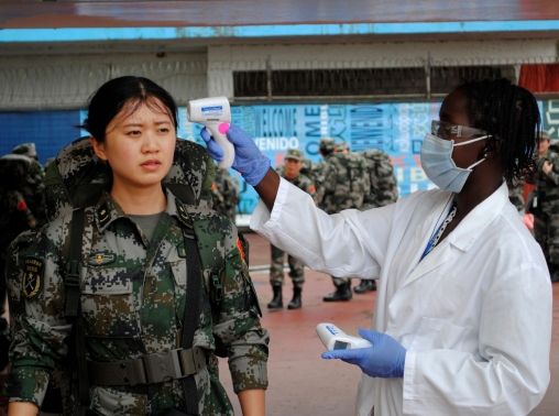 A Chinese military health worker, part of a delegation sent by China to help in the fight against Ebola, has her temperature taken as she arrives at Roberts airport outside Monrovia, November 15, 2014