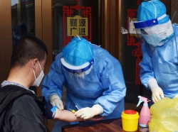 A worker from the city's center for disease control and prevention draws blood from a man to conduct a test for antibodies against COVID-19 in Suifenhe, China, April 16, 2020, photo by Huizhong Wu/Reuters