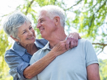 A happy older couple embraces and smiles