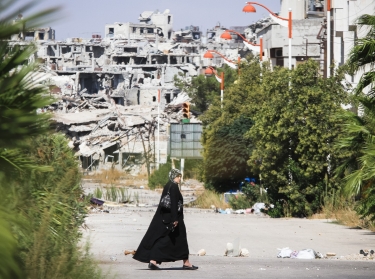 A woman walks near a residential area in the city of Homs destroyed in the fighting between the rebels of the Syrian National Army