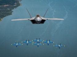 Maj. Paul Lopez, F-22 Demonstration Team commander, flies above the U.S. Navy Blue Angels' iconic diamond formation over Beaufort, S.C., April 25, 2019. The historic flight featured two of the world's premier aerial demonstration teams side-by-side for the first time ever. (U.S. Air Force photo by 2nd Lt. Samuel Eckholm)