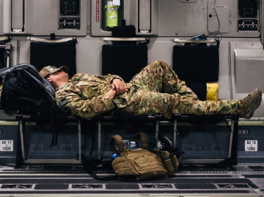 A U.S. Air Force Airman sleeps inside a C-17 Globemaster during a flight