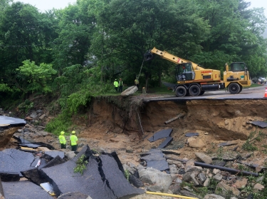 A crew works to repair a road destroyed by flooding on May 31, 2018 in Ellicott City, Maryland. On May 27 Ellicott City experienced a devastating flood for the second time in two years. 