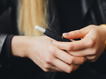 A close-up image of hands holding an electronic cigarette. Photo by SHipskyy / Getty Images