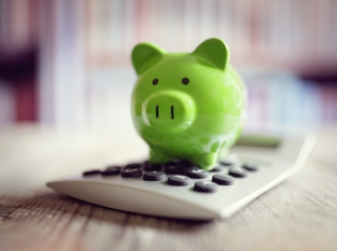 A green piggy bank on a calculator