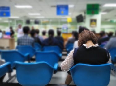 Woman sits on a blue chair waiting for the emergency room, photo by toodtuphoto/Adobe Stock