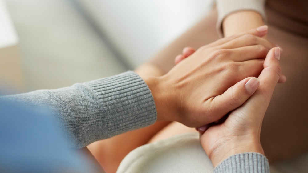 Woman holding another's hands, showing compassion, photo by pressmaster/Adobe Stock