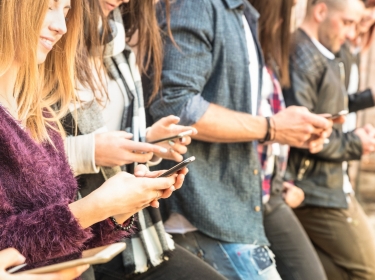 Young adults using smartphones at university college backyard break