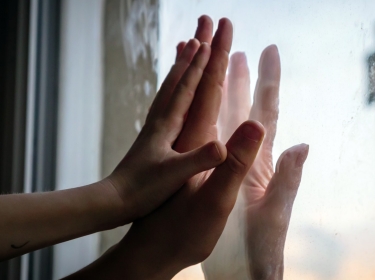 Hands of women and a child on opposite sides of window pane,  photo by Jevanto Productions/Adobe Stock