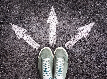 Shoes and arrows pointing in different directions on asphalt floor, photo by Delphine Poggianti/Adobe Stock