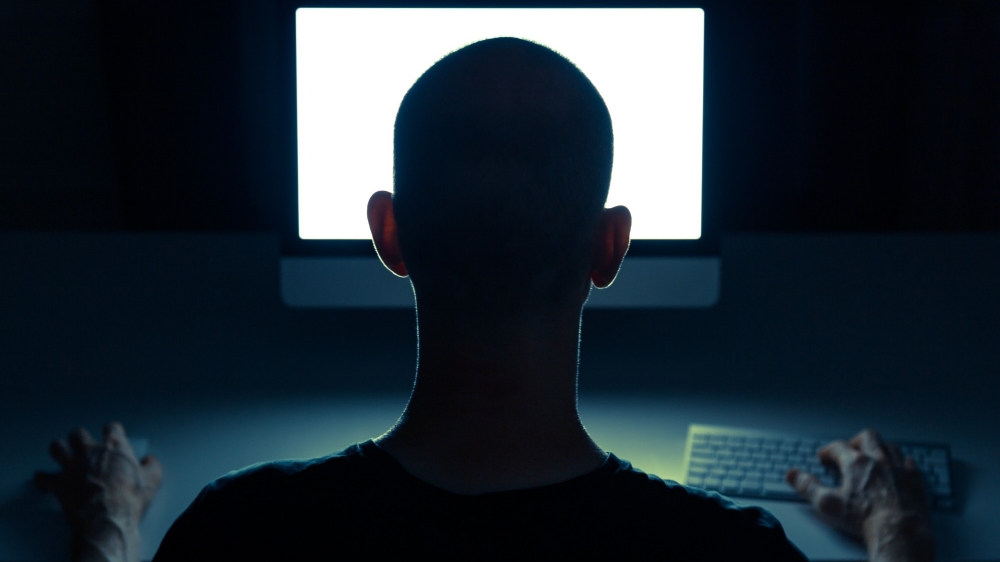 Silhouette of man in front of computer screen, photo by Sander van der Werf/Adobe Stock