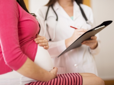 Pregnant woman visiting doctor for checkup, photo by Halfpoint/Adobe Stock