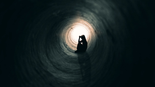 A woman sitting in a dark tunnel